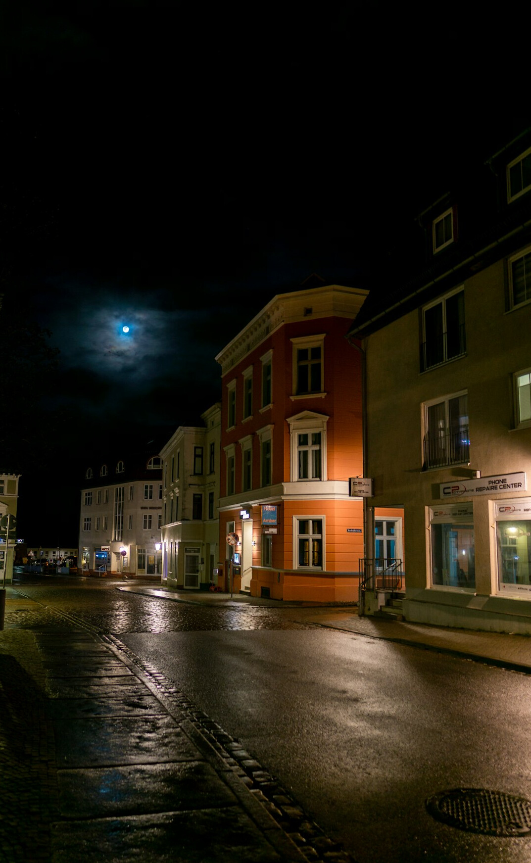 Empty city street at night under a full moon